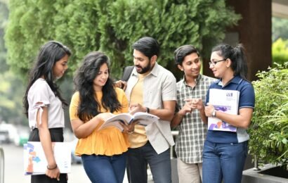 A group of diverse college students engaged in outdoor group study session, sharing books and ideas.
