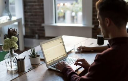 man operating laptop on top of table