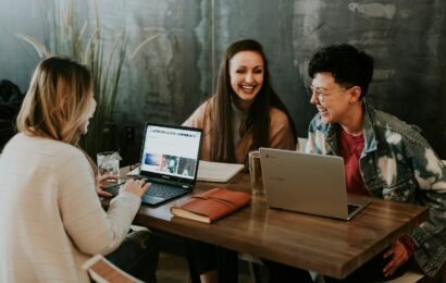 three people sitting in front of table laughing together