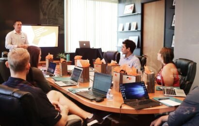 man standing in front of people sitting beside table with laptop computers